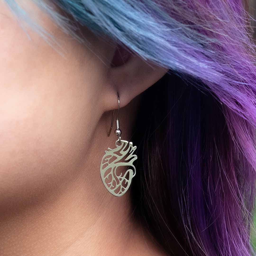 Anatomical Heart Earrings in silver colored steel, being worn by a model. Anatomically correct, they make a unique science jewelry gift!