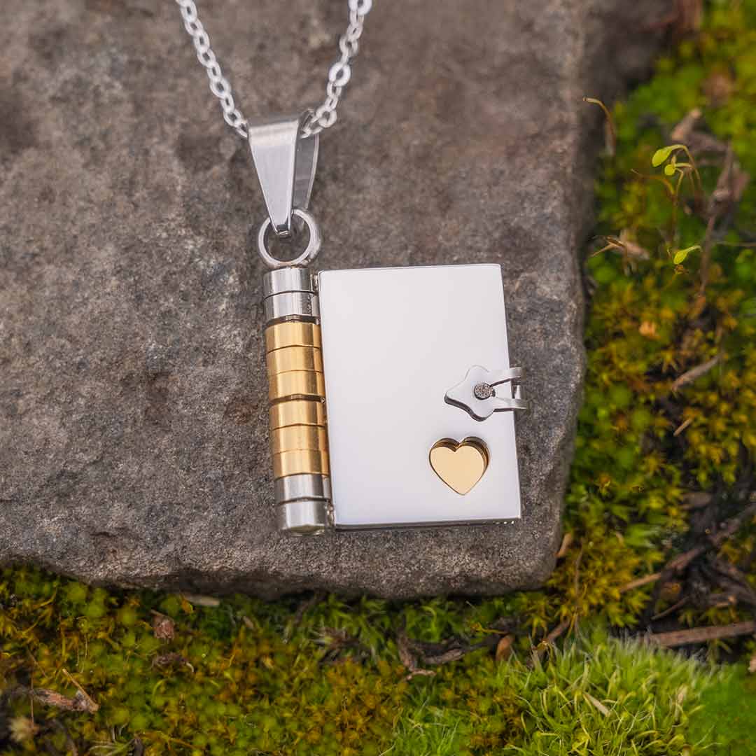 Book Necklace - jewelry gift for a writer, librarian, teacher, historian, or book lover. Photo of book pendant on a stone background, with green moss surrounding it.