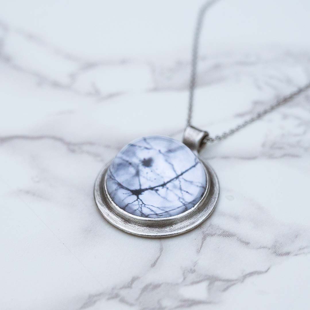 Neuron necklace: science jewelry for biology and neuroscience. Great gift for teachers, biologists, nurses, and neuroscientists. Pyramidal neuron under a glass dome with a steel chain.