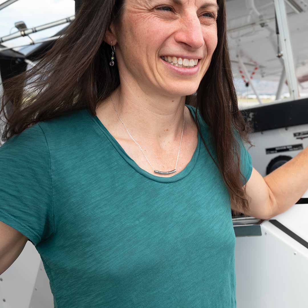 Woman wearing ALIS VOLAT PROPRIIS Necklace in front of an airplane
