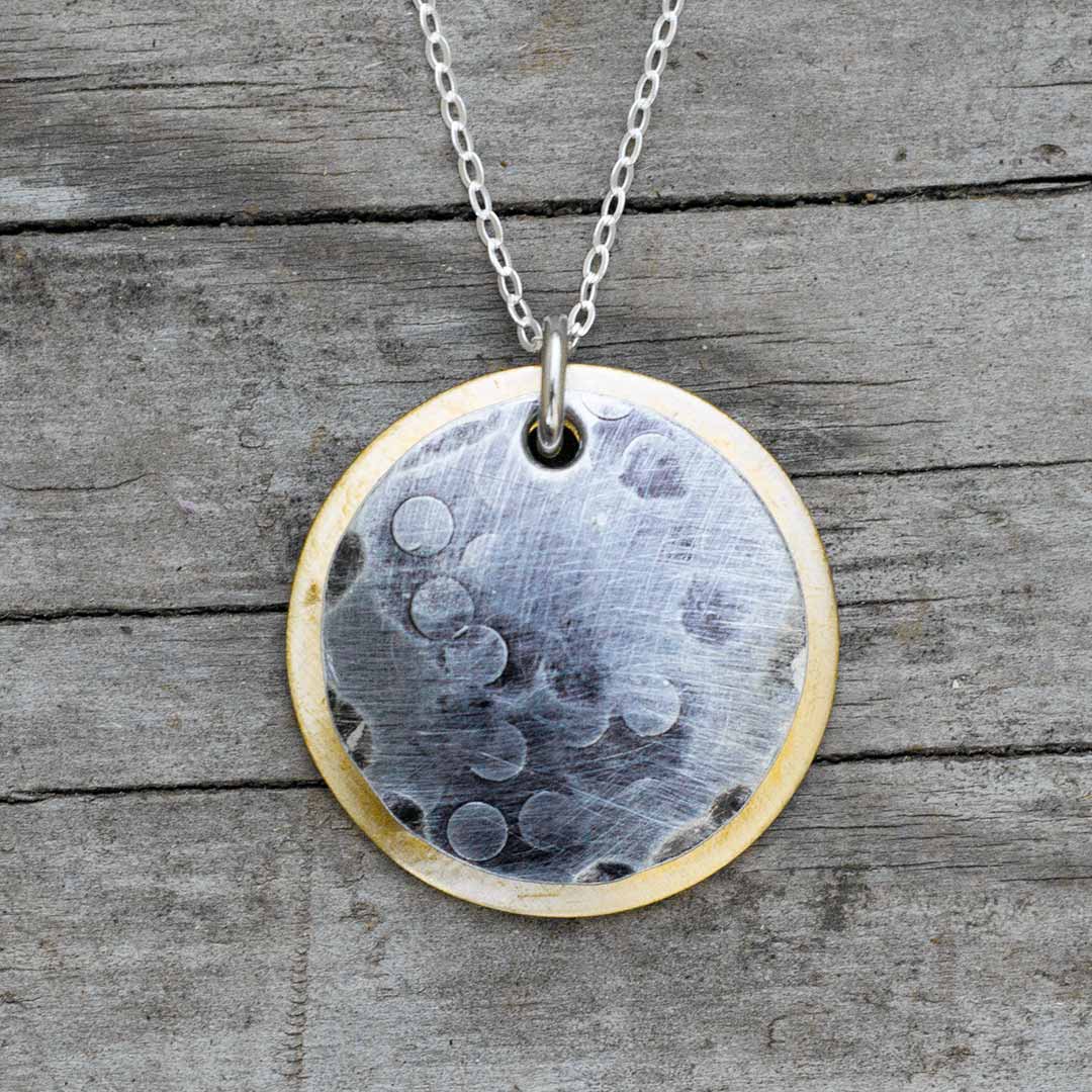 Solar eclipse necklace, science jewelry for astronomers, teachers, students, and astronomy enthusiasts. Made from an antiqued silver aluminum disc over a weathered brass disc.