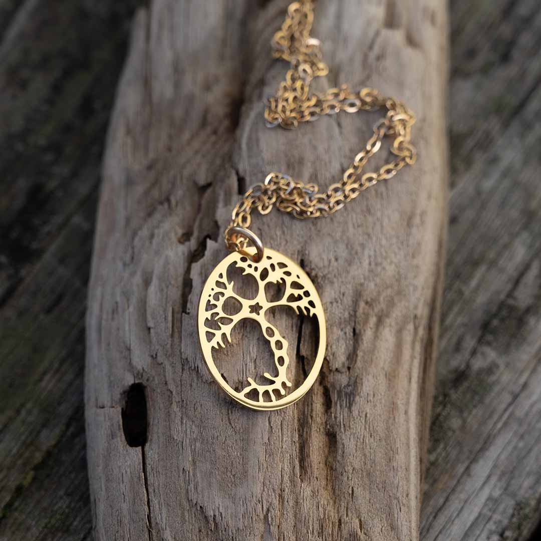 Gold plated pyramidal neuron necklace resting elegantly on a brown piece of driftwood. 