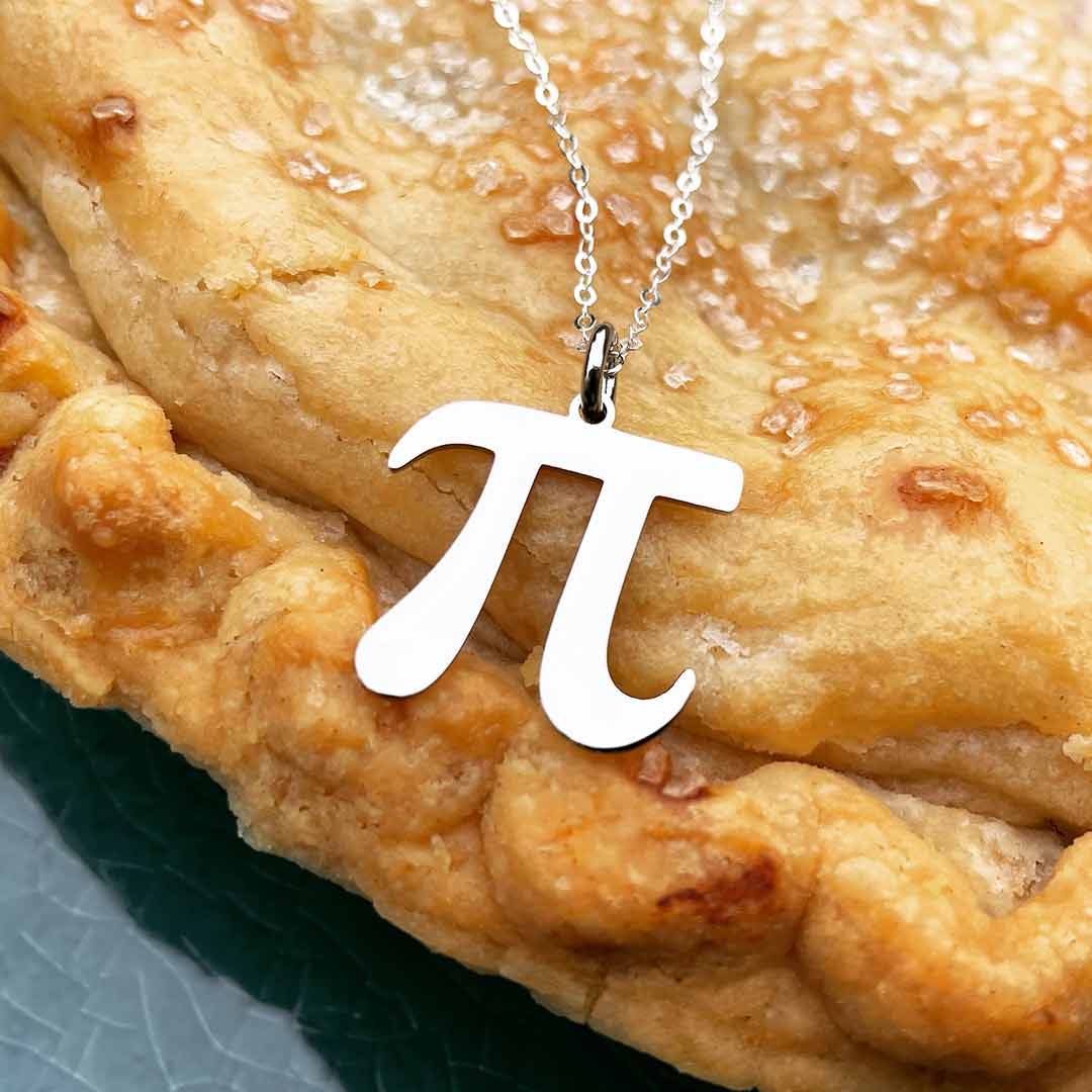 Silver Pi Necklace on a background of pie crust, looking mathematically delicious - math jewelry using the pi symbol. Great gift for a student or teacher of mathematics. Silver steel on a sterling silver chain.